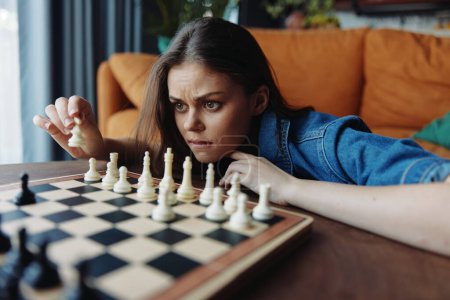 Mujer joven jugando un juego estratégico de ajedrez en una acogedora sala de estar con un sofá en el fondo
