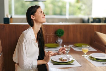Foto de Cena romántica en casa Mujer disfrutando de una deliciosa comida con vino y pastel en una mesa de comedor festiva - Imagen libre de derechos