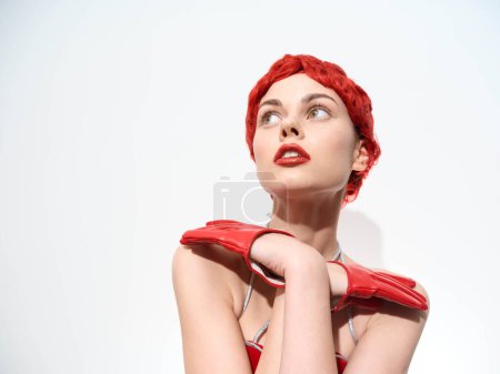Elegant woman with red hair and gloves posing against white background in studio photoshoot
