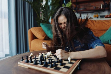 Foto de Mujer disfrutando de una partida de ajedrez en un tablero de madera en una acogedora sala de estar - Imagen libre de derechos