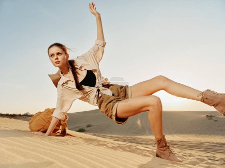 Téléchargez les photos : Solo voyageuse debout sur une dune de sable dans le désert sous le soleil brûlant - en image libre de droit