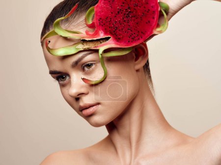 Primer plano de la hermosa joven con sandía en la cabeza, posando sobre fondo beige, concepto de fruta de verano