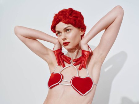 Photo for Sensual redhaired woman in heart shaped bra posing for photoshoot in studio with professional lighting and backdrop - Royalty Free Image