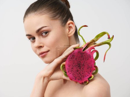 Photo for Beautiful young woman holding a vibrant dragon fruit against a clean white background, isolated image for stock photo websites - Royalty Free Image