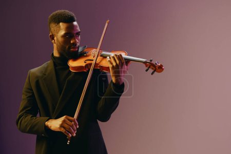 Photo for Elegant African American Man in Black Suit Playing Violin Against Purple Background in Studio Setting - Royalty Free Image
