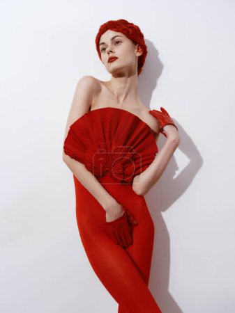 Foto de Mujer segura en vestido rojo y sombrero pose llamativa para la cámara con las manos en las caderas - Imagen libre de derechos