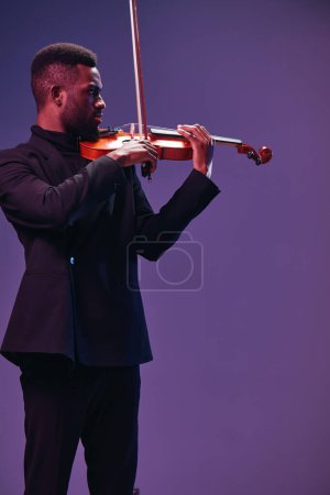 Elegante músico de traje negro tocando violín bajo luces púrpuras con fondo artístico