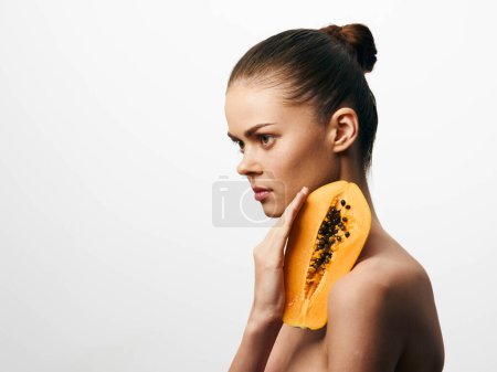 Téléchargez les photos : Belle jeune femme tenant des fruits frais de papaye sur fond blanc, mode de vie sain et concept de soins de la peau - en image libre de droit
