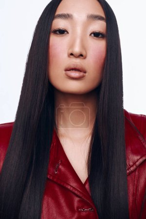 Stilvolle Asiatin in roter Lederjacke mit langen schwarzen Haaren posiert für die Kamera