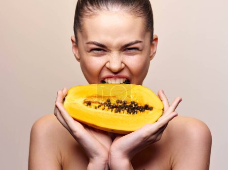 Photo for Woman holding a fresh papaya in front of her face with wide open mouth, isolated on white background - Royalty Free Image