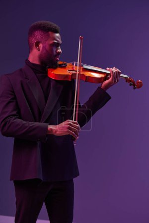 Téléchargez les photos : Talentueux jeune homme afro-américain jouant du violon avec passion sur fond violet vif, concept de performance musicale artistique - en image libre de droit