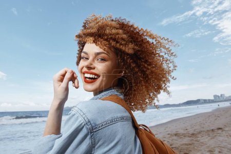 Téléchargez les photos : Femme souriante avec sac à dos, profiter de vacances heureuses sur une plage - en image libre de droit