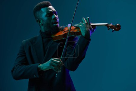 Foto de Talentoso hombre afroamericano en traje negro tocando el violín sobre un fondo azul vibrante, concepto artístico de interpretación musical - Imagen libre de derechos