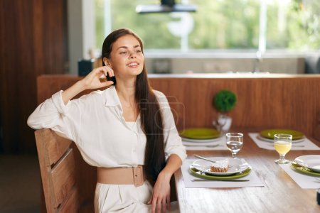Foto de Mujer feliz disfrutando de una cena romántica en casa con una deliciosa comida en la mesa de comedor Ella sonríe extáticamente mientras se entrega a un pastel casero y una copa de vino, creando una moda y elegante - Imagen libre de derechos
