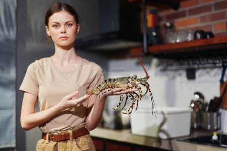 Foto de Mujer sosteniendo una langosta en su mano en un ambiente de cocina casera - Imagen libre de derechos