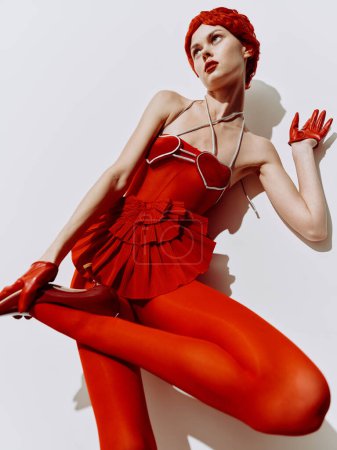 Téléchargez les photos : Femme élégante dans une robe rouge couchée sur le sol avec les mains sur les genoux dans une pose gracieuse - en image libre de droit