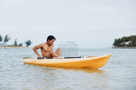 Téléchargez les photos : Happy Asian Man kayak sur une plage tropicale - Profiter des vacances d'été aventure - en image libre de droit