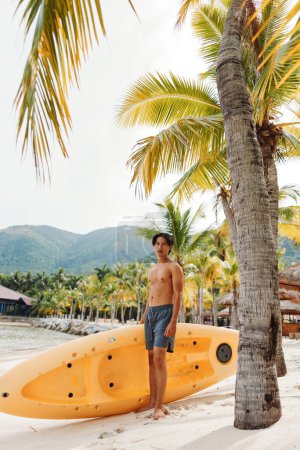 Photo for Kayak Adventures: Happy Asian Man Enjoying Water Sport Activity at Tropical Beach - Royalty Free Image