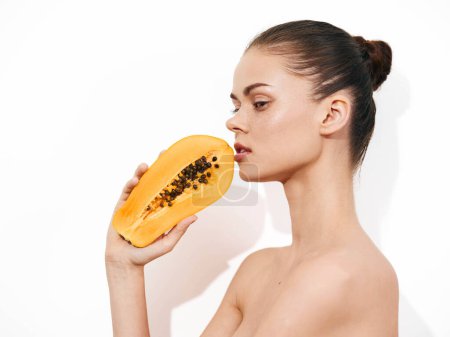 Téléchargez les photos : Belle jeune femme appréciant l'arôme de fruits frais de papaye dans un cadre de studio sur fond blanc - en image libre de droit