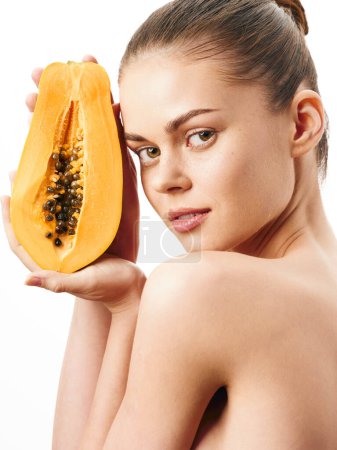 Téléchargez les photos : Femme exotique tenant un fruit tropical devant son visage avec la poitrine nue exposée dans le concept de photo artistique - en image libre de droit