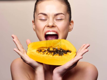 Foto de Mujer con la boca abierta sosteniendo una papaya frente a su cara con expresión de ojos anchos - Imagen libre de derechos