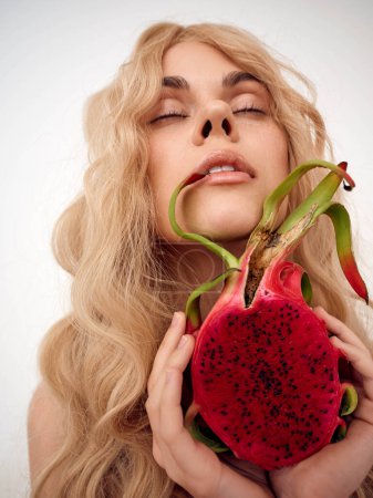 Téléchargez les photos : Femme blonde tenant une tranche de pastèque devant son visage, regardant joyeuse et estivale - en image libre de droit