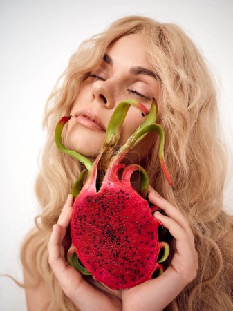 Téléchargez les photos : Belle femme aux longs cheveux blonds tenant une tranche de pastèque devant son visage - en image libre de droit