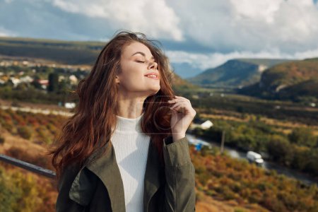 Téléchargez les photos : Belle jeune femme debout sur un pont en contemplation avec les yeux fermés sous le ciel ouvert - en image libre de droit