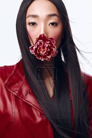 Elegant woman with long black hair wearing a red leather jacket and holding a flower in her mouth