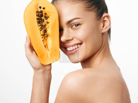 Téléchargez les photos : Portrait of a woman holding a ripe papaya fruit in front of her face on a white background - en image libre de droit