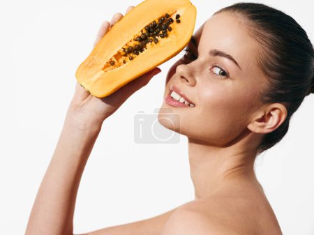 Téléchargez les photos : Woman holding ripe papaya and looking up at camera in natural daylight setting - en image libre de droit
