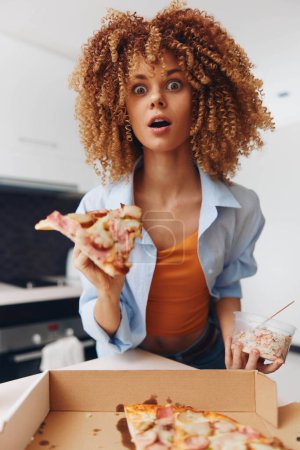 Junge Frau mit lockigem Haar genießt ein Stück Pizza vor einem Karton