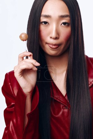 Téléchargez les photos : Portrait d'une femme aux longs cheveux noirs tenant une brosse à dents devant son visage dans une veste rouge - en image libre de droit