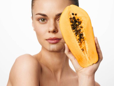Téléchargez les photos : Woman holding papaya in front of face with hands on head in tropical setting - en image libre de droit