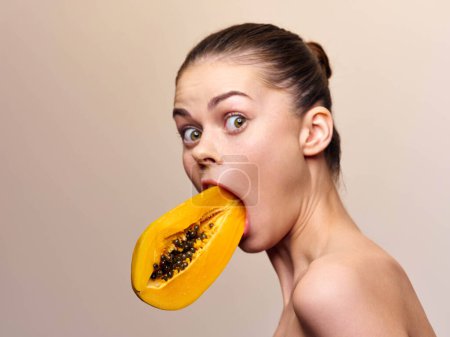 Téléchargez les photos : Woman holding a papaya in her mouth while holding another piece of fruit in her hand - en image libre de droit