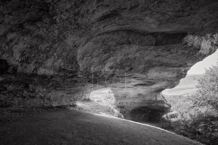 Explorer les profondeurs mystiques une photo en noir et blanc d'une grotte avec la lumière coulant dans
