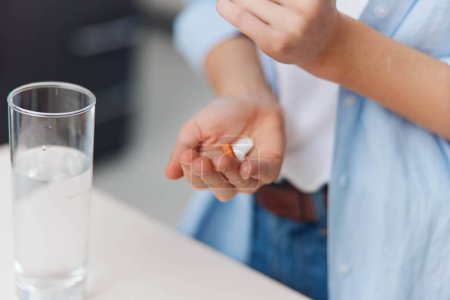Téléchargez les photos : Femme tenant une pilule devant un verre d'eau, de soins de santé et de médecine concept - en image libre de droit