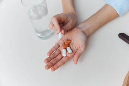 Téléchargez les photos : Womans hands holding pills and glass of water on white table Healthcare, medication, treatment concept - en image libre de droit