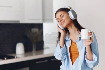 Téléchargez les photos : Woman enjoying music and coffee in stylish kitchen interior with modern design and cozy atmosphere - en image libre de droit
