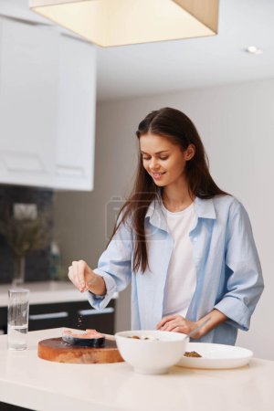 Foto de Mujer de Camisa Azul Preparando Comida en Contador en Cocina Blanca Cocina y Concepto Culinario Foto - Imagen libre de derechos