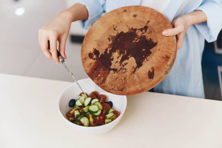 Foto de Mujer sosteniendo ensaladera fresca en el mostrador de madera en la cocina para un concepto de alimentación saludable - Imagen libre de derechos