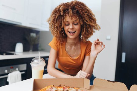 Foto de Young woman with curly hair enjoying a delicious pizza at a table in a cozy restaurant setting - Imagen libre de derechos