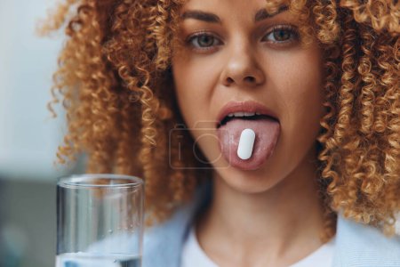 Woman with curly hair sticking out tongue holding a pill, concept of playful defiance against medication