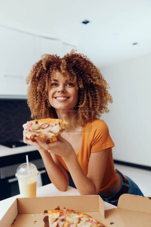Photo for Curly haired woman holding a slice of pizza in front of a box, isolated on white background - Royalty Free Image