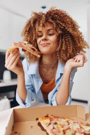 Happy woman enjoying a delicious slice of pizza in front of a tempting box of pizza with curly hair in focus