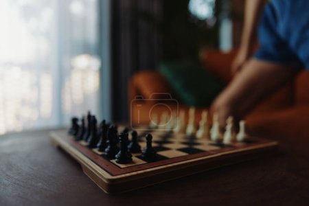 Photo for The strategic game of chess being played by a person in front of a window on a table - Royalty Free Image