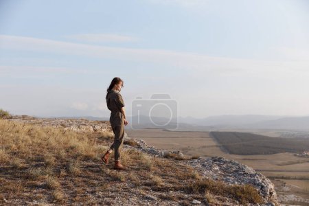 Woman standing on hill overlooking valley and mountains in a stunning landscape view of nature and travel beauty