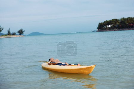 Téléchargez les photos : Vacances actives : L'homme asiatique profite de l'aventure de kayak sur la plage tropicale - en image libre de droit