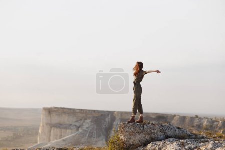 Au sommet du monde femme embrassant la liberté et l'aventure dans la nature au sommet de la montagne avec les bras tendus
