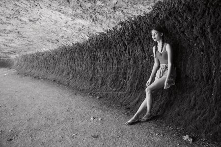 Woman sitting in front of wall in black and white photo, reflecting on life and time spent traveling